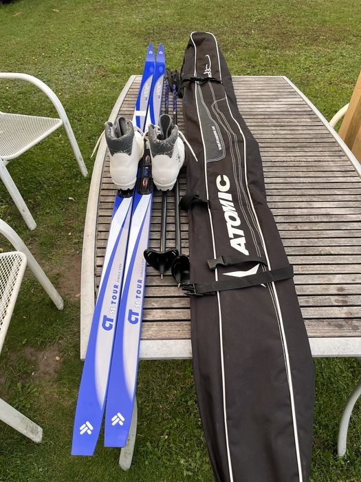 Zestaw narty biegowe, kijki, buty i pokrowiec.