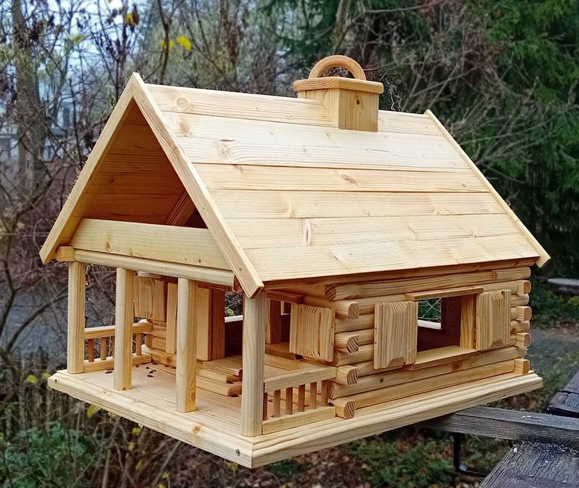 Karmnik dla ptaków. Domek z bala z okiennicami i zasobnikiem