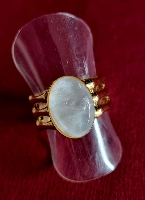 Anel dourado, em aço, com uma madrepérola oval.  Ajustável