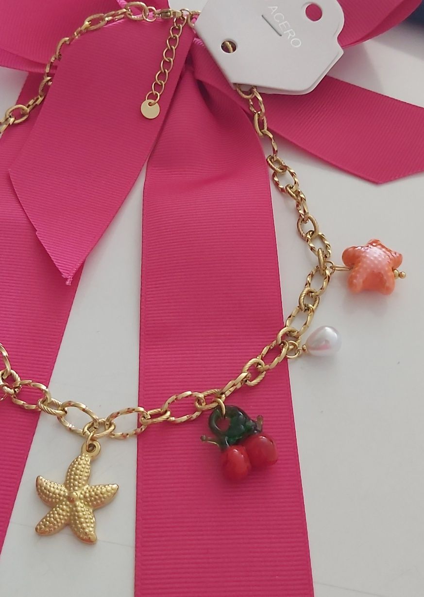 Colar dourado, em aço, com 7 pingentes diferentes. Tem extensor