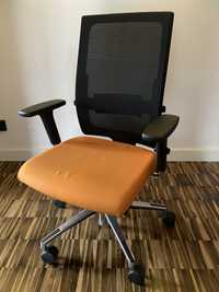 Krzesło obrotowe z pomarańczowym siedziskiem.