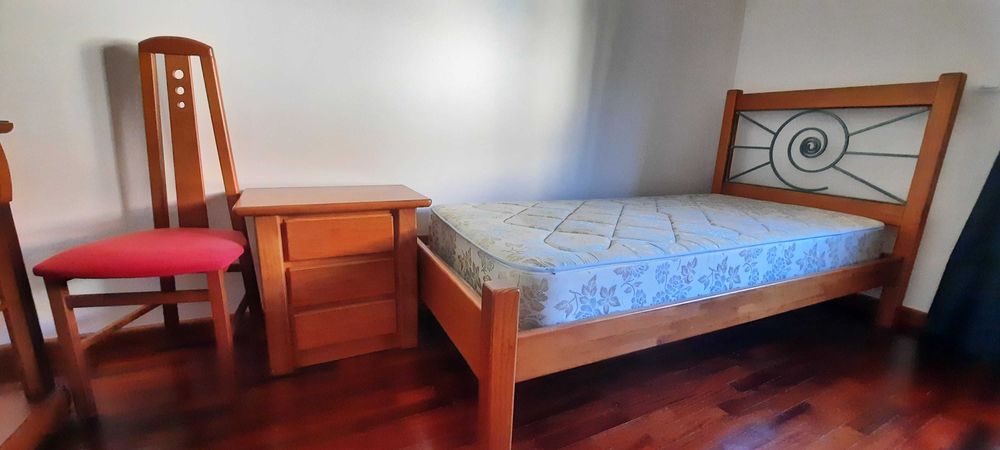 Cama de madeira com colchão e mesa de cabeceira