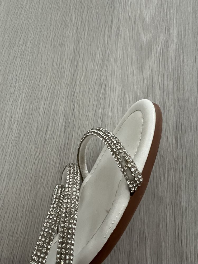 Białe sandały na płaskiej podeszwie z ozdobnymi paskami i sprzączką