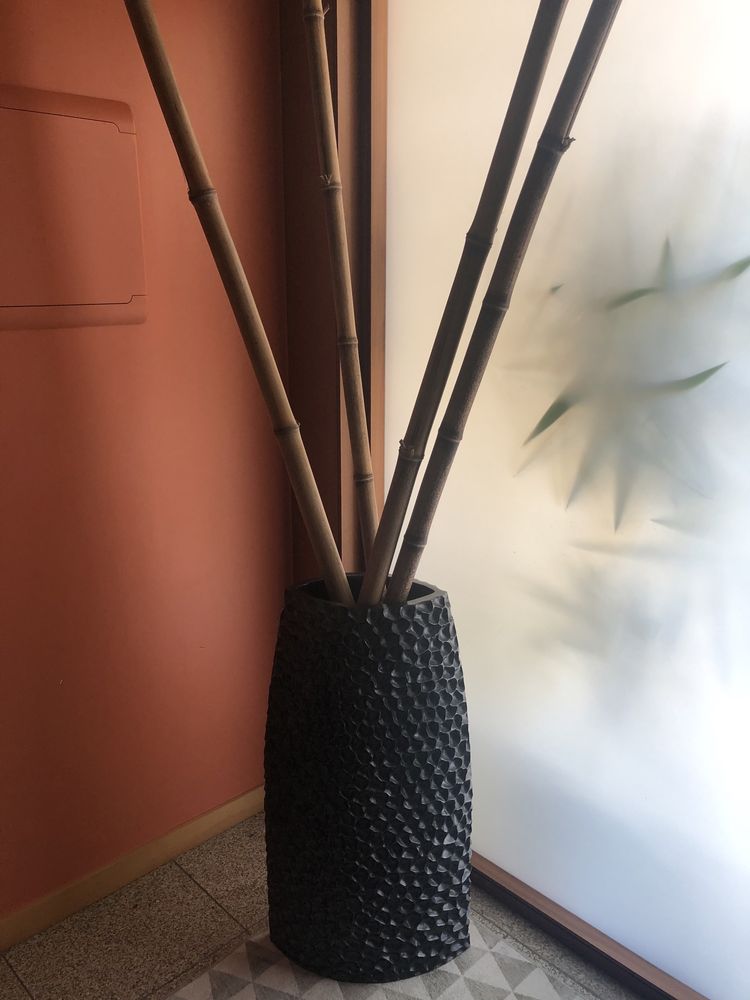 Peça de cerâmica castanha com 4 canas de bambu.