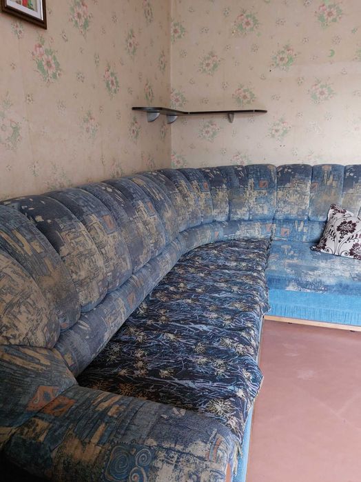 Кутовий диван, синього кольору, зручний для відпочинку.