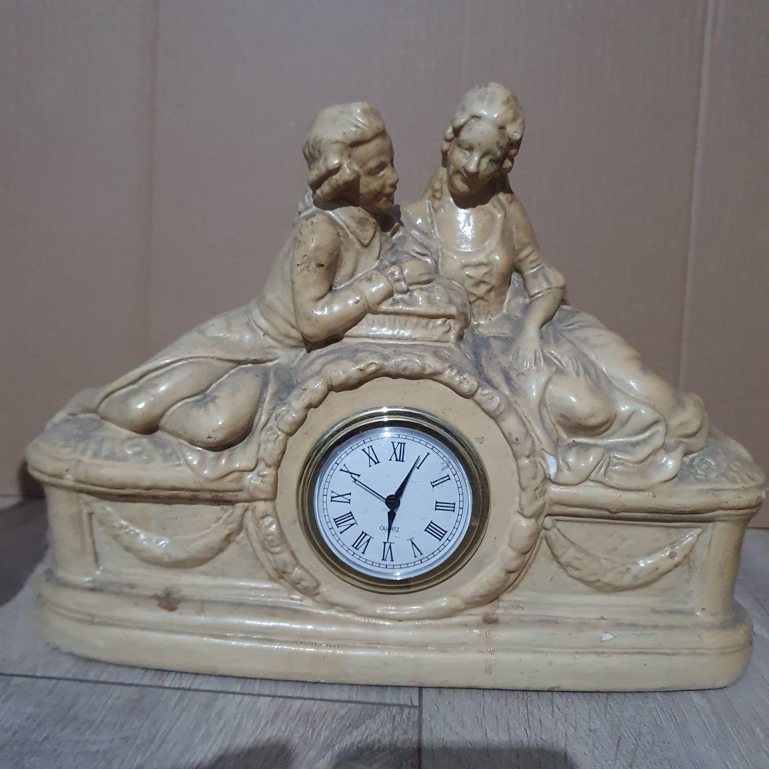 Stary ceramiczny zegar z dwoma figurkami.