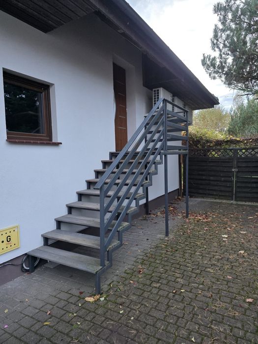 Schody zewnętrzne z metalowa barierką.