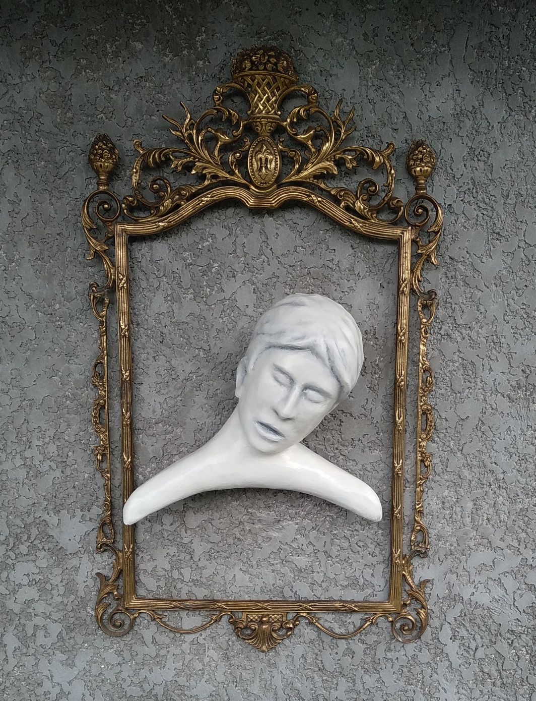 Escultura com moldura em metal amarelo