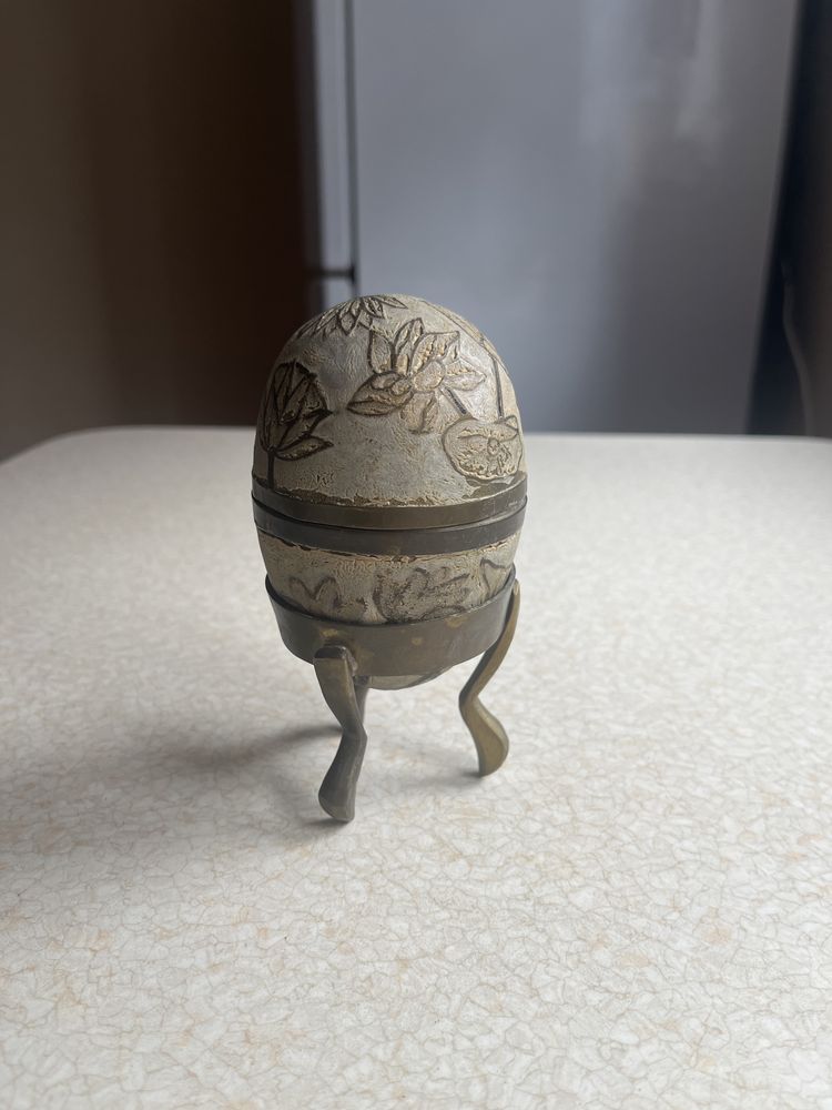 Mosiężne jajko ze wzormi na podstawce 14 cm wysokości.