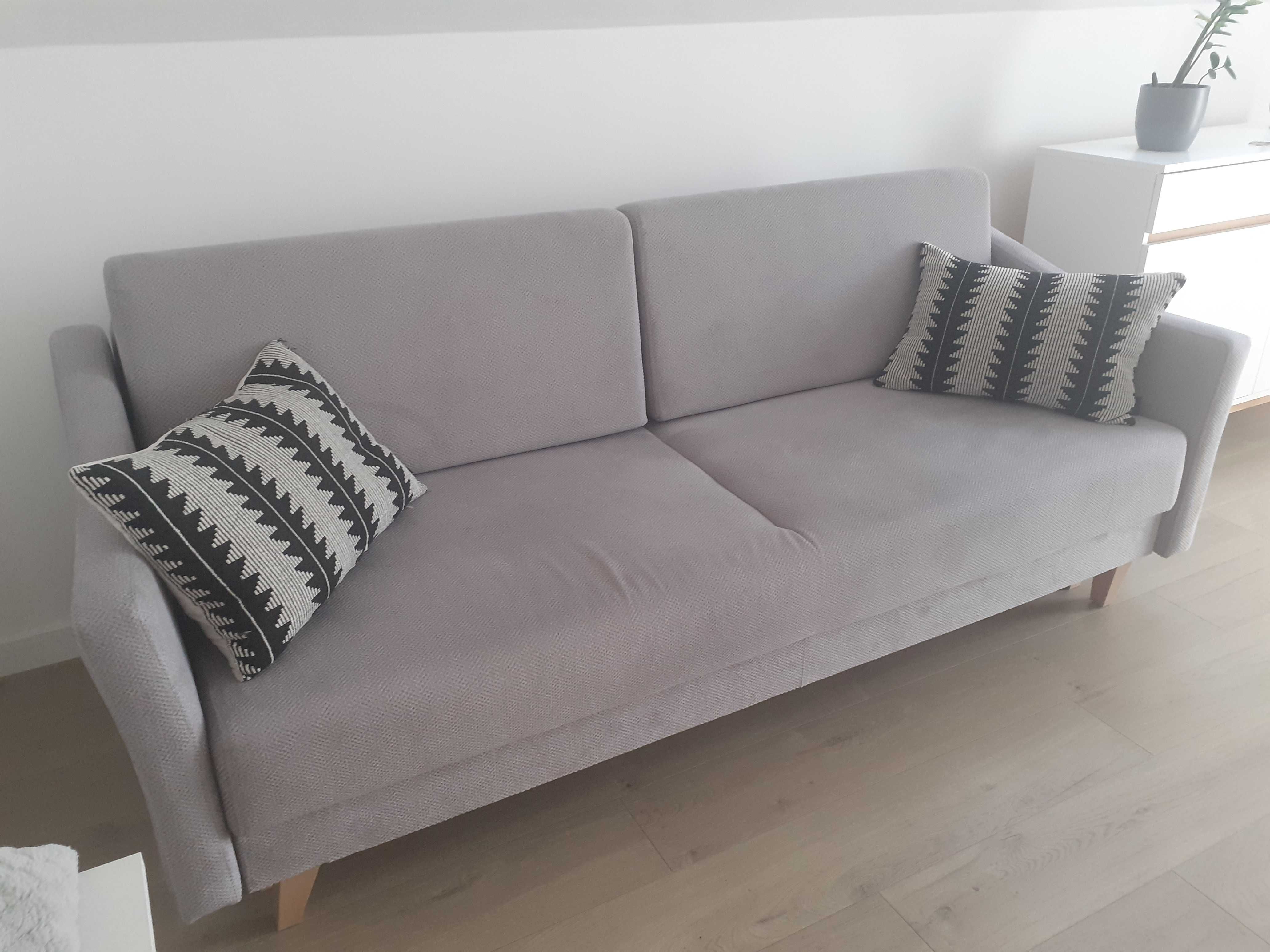 Szara sofa rozkładana z pojemnikiem na pościel