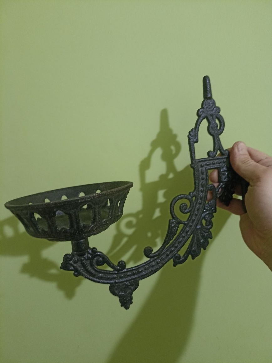 Stary masywny metalowy świecznik do powieszenia na ścianę.