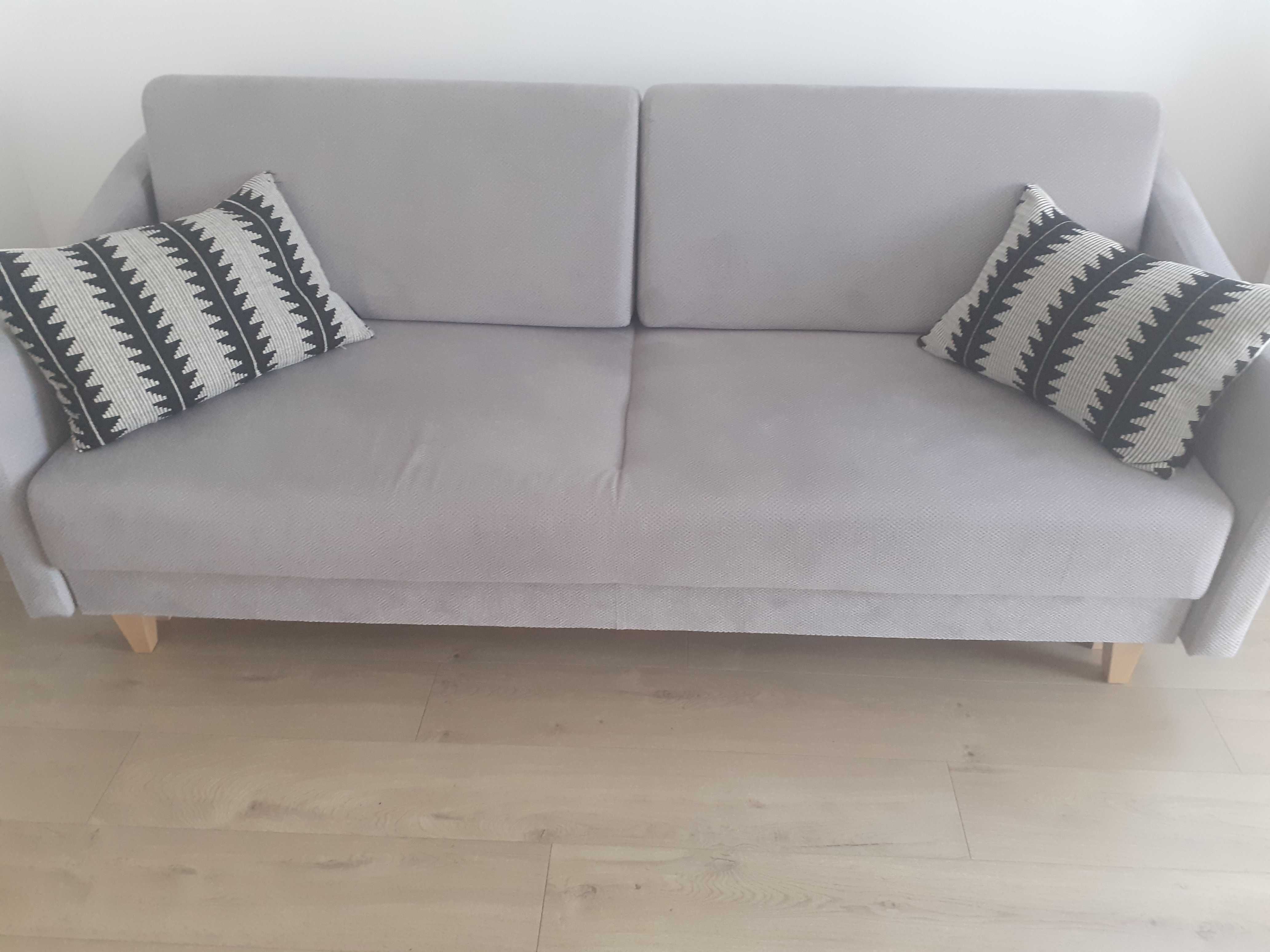 Szara sofa rozkładana z pojemnikiem na pościel