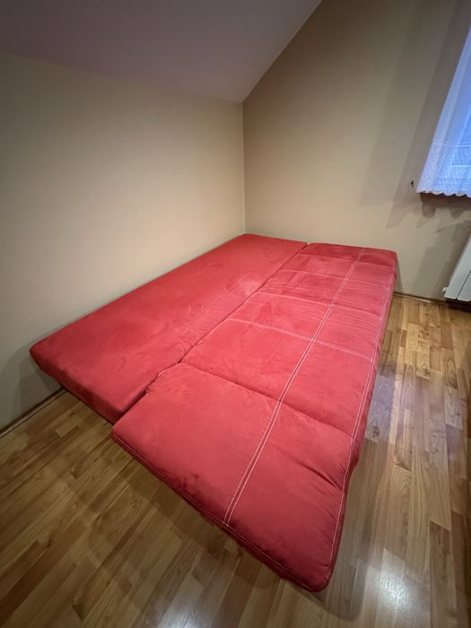 Czerwona kanapa z funkcja spania i pojemnikiem na pościel