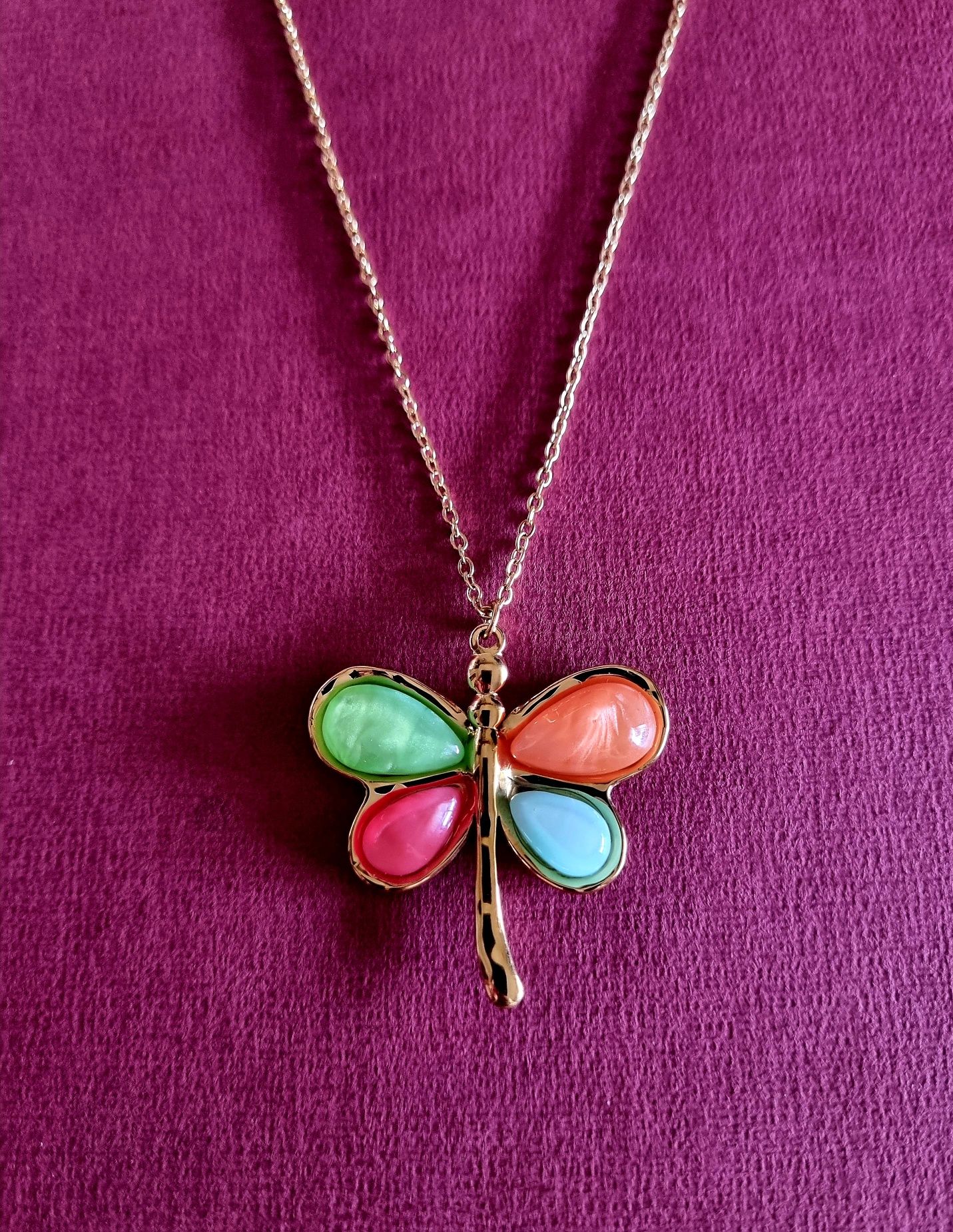 Colar dourado, em aço, com libelinha colorida. Tem extensor