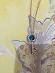 Colar/fio dourado com uma chave com pedra azul