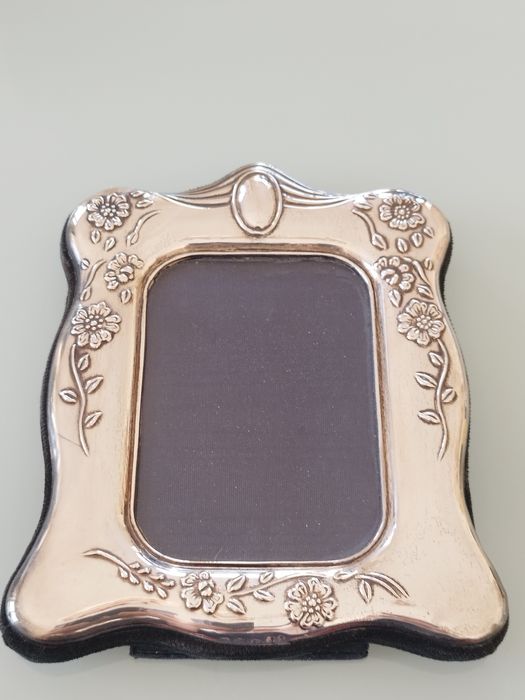 Moldura delicada com detalhes florais em relevo.

- Material: Prata
-