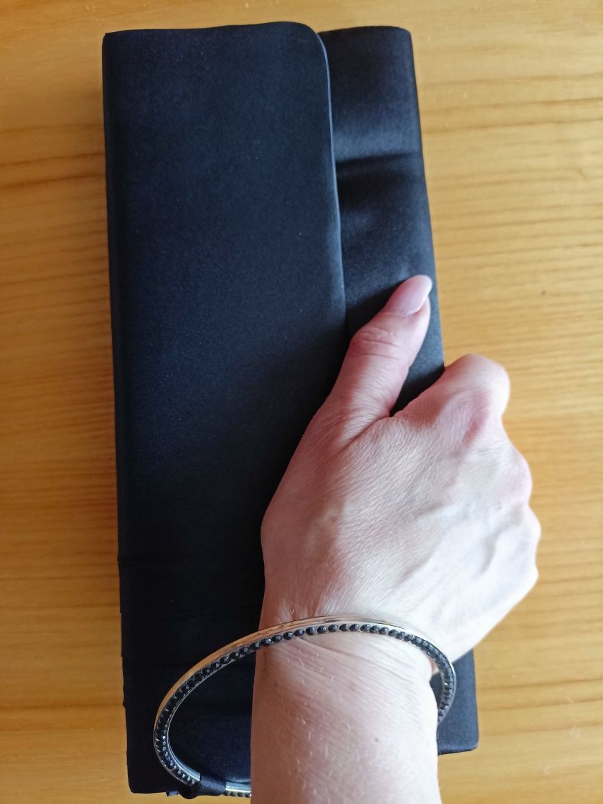 Czarna kopertówka z ozdobną bransoletą na nadgarstek