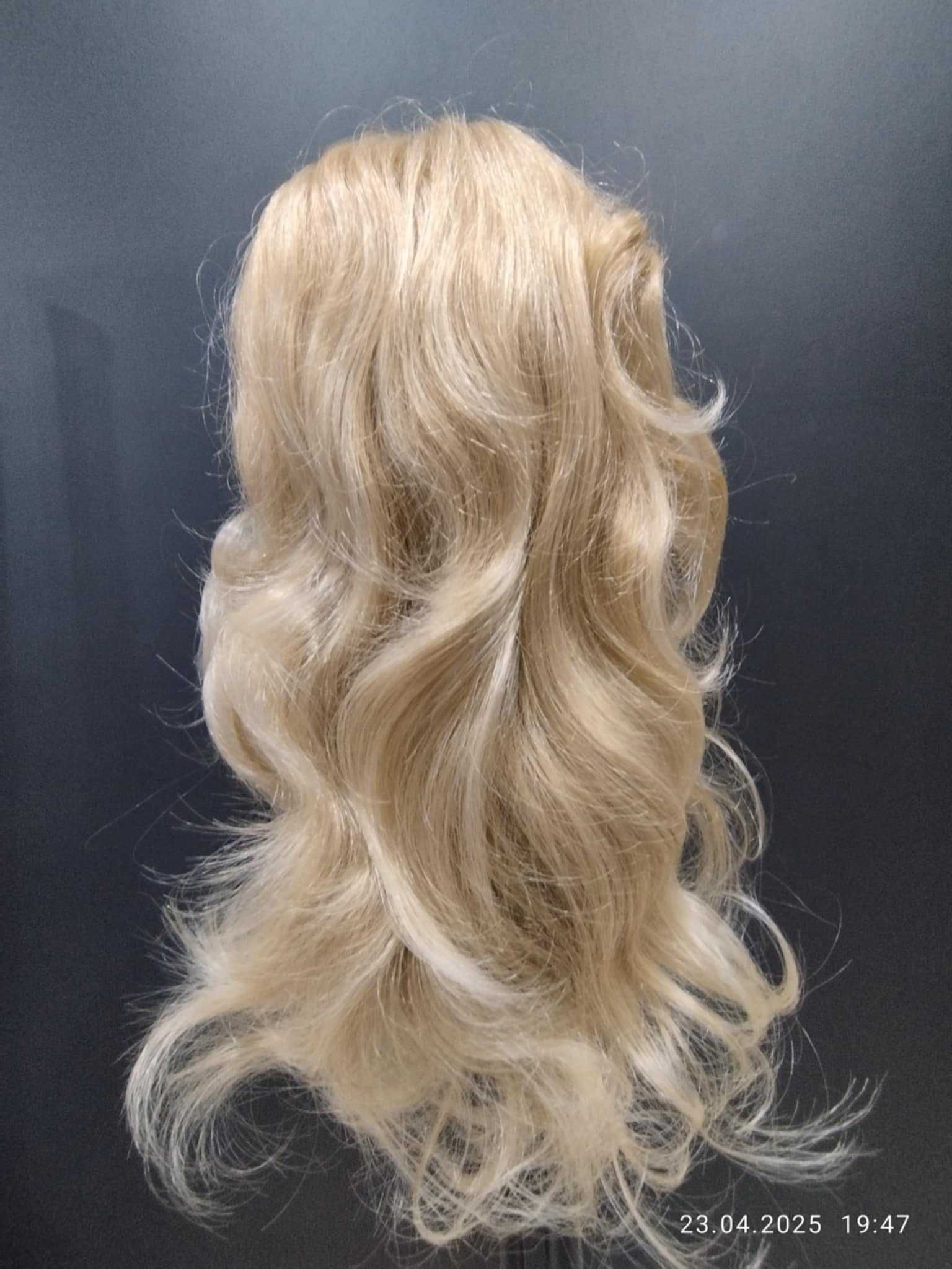 Peruka. Włosy długie cieniowane, delikatnie falowane. Kolor blond.