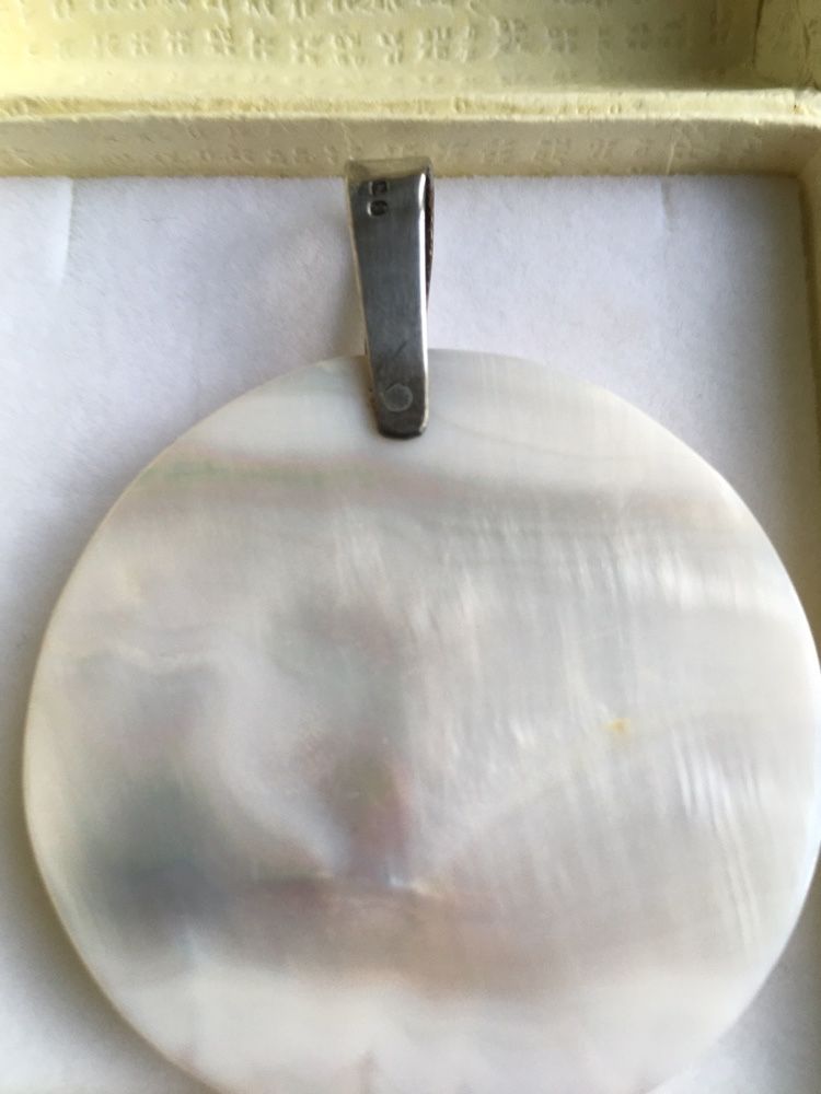 Medalha de prata e madrepérola, com a letra C.