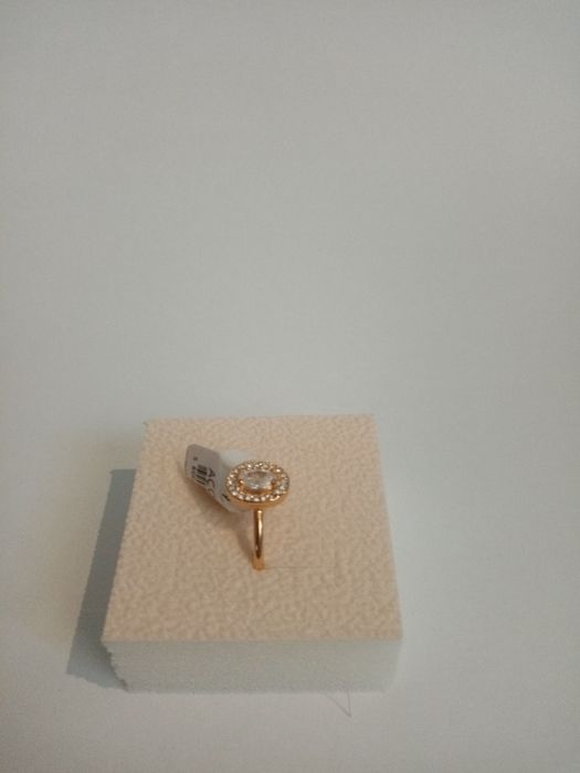 Anel dourado com pequenos cristais a rodear um cristal grande.