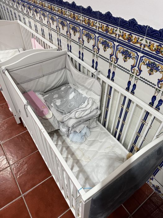 Dois berços estufados em cinza com colchão e roupa de cama