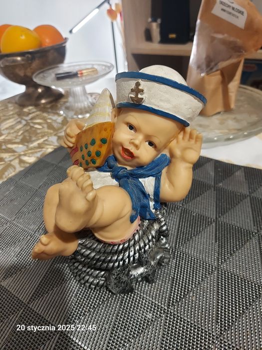 Figurka dekoracyjna chłopiec w marynarskiej czapce z łódką na plaży