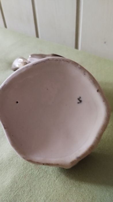 Porcelanowa figurka sroki na krawędzi podstawy.