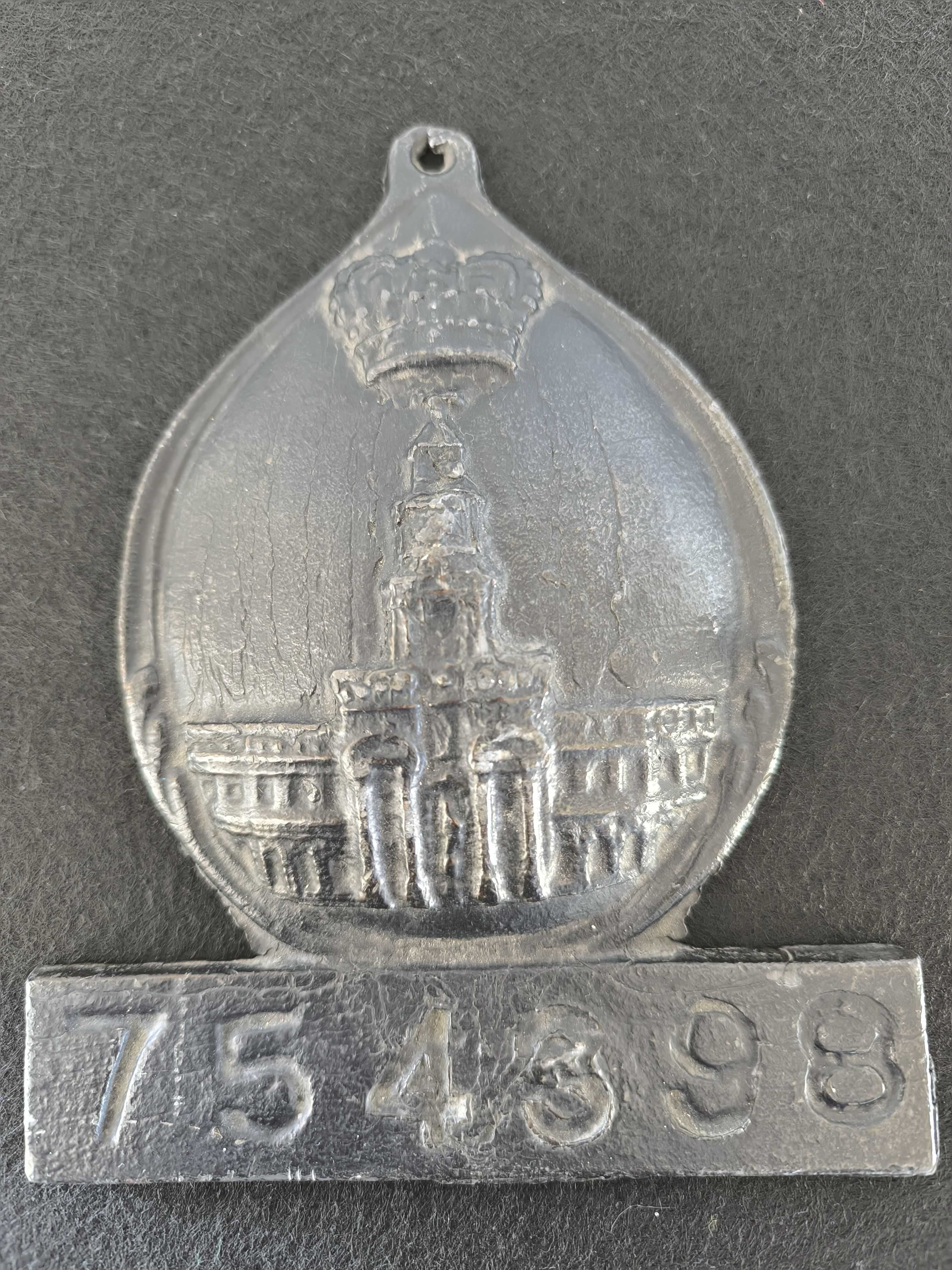 Placa de metal com o n.º 754398, marcada com o emblema da seguradora