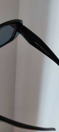 Óculos Prada preto com logótipo dourado.
