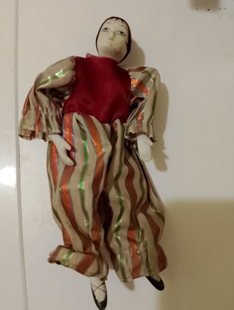 Stary klaun-zabawka z porcelanową głową, rękami i nogami.