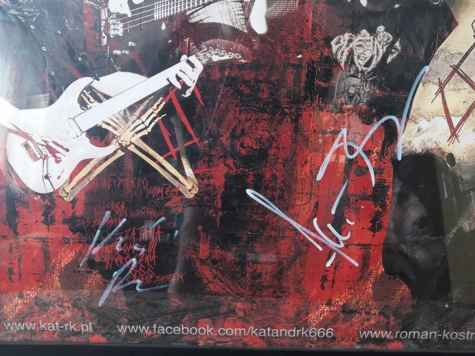 Plakat grupy KAT z autografami grupy w ramie.