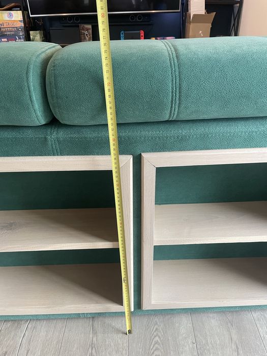Zielona butelkowa sofa z funkcja spania z pufami i drewnianymi półkami
