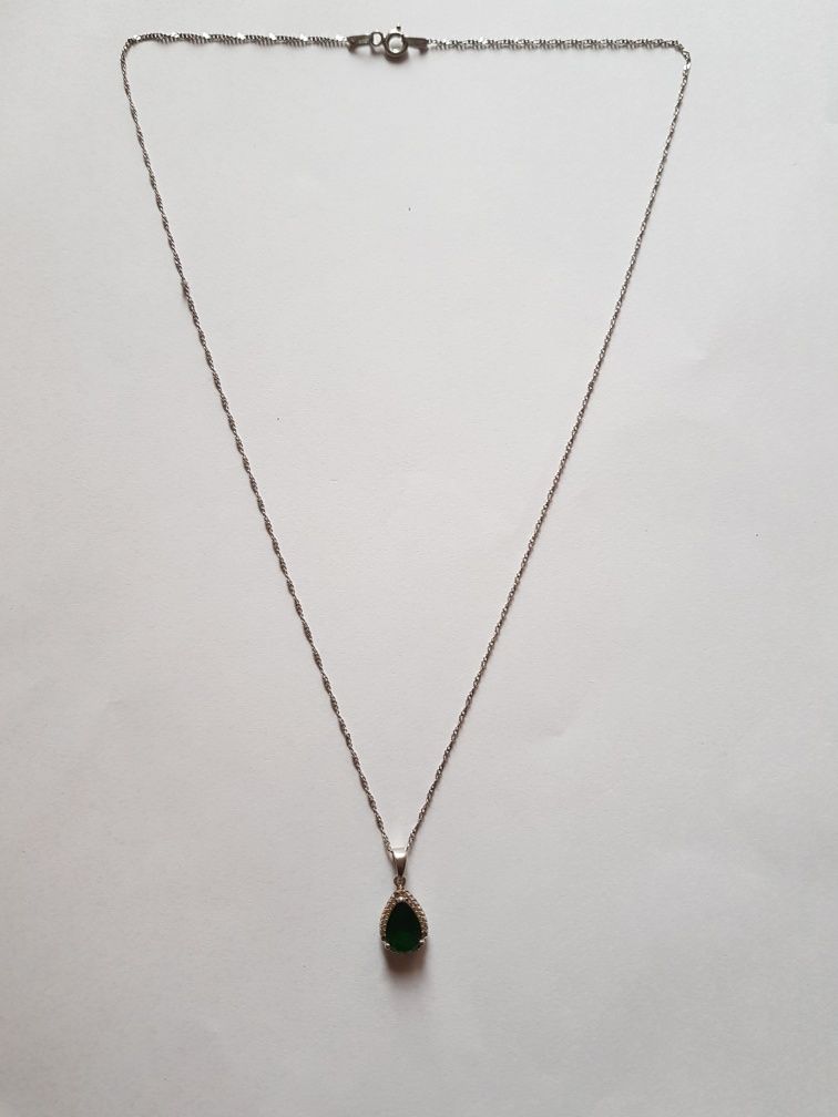 Srebrna zawieszka z zielonym kamieniem i srebrnym łańcuszkiem.