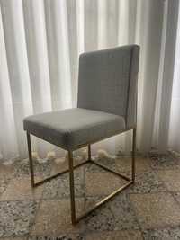 Cadeira em inox com acabamento dourado e cobertura em tecido