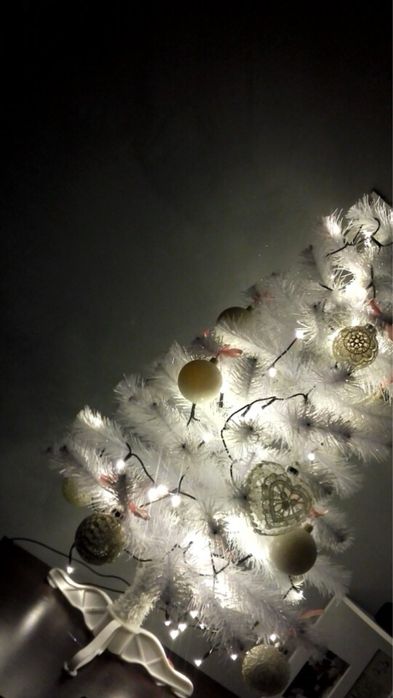 Biała sztuczna choinka z bombkami i lampkami