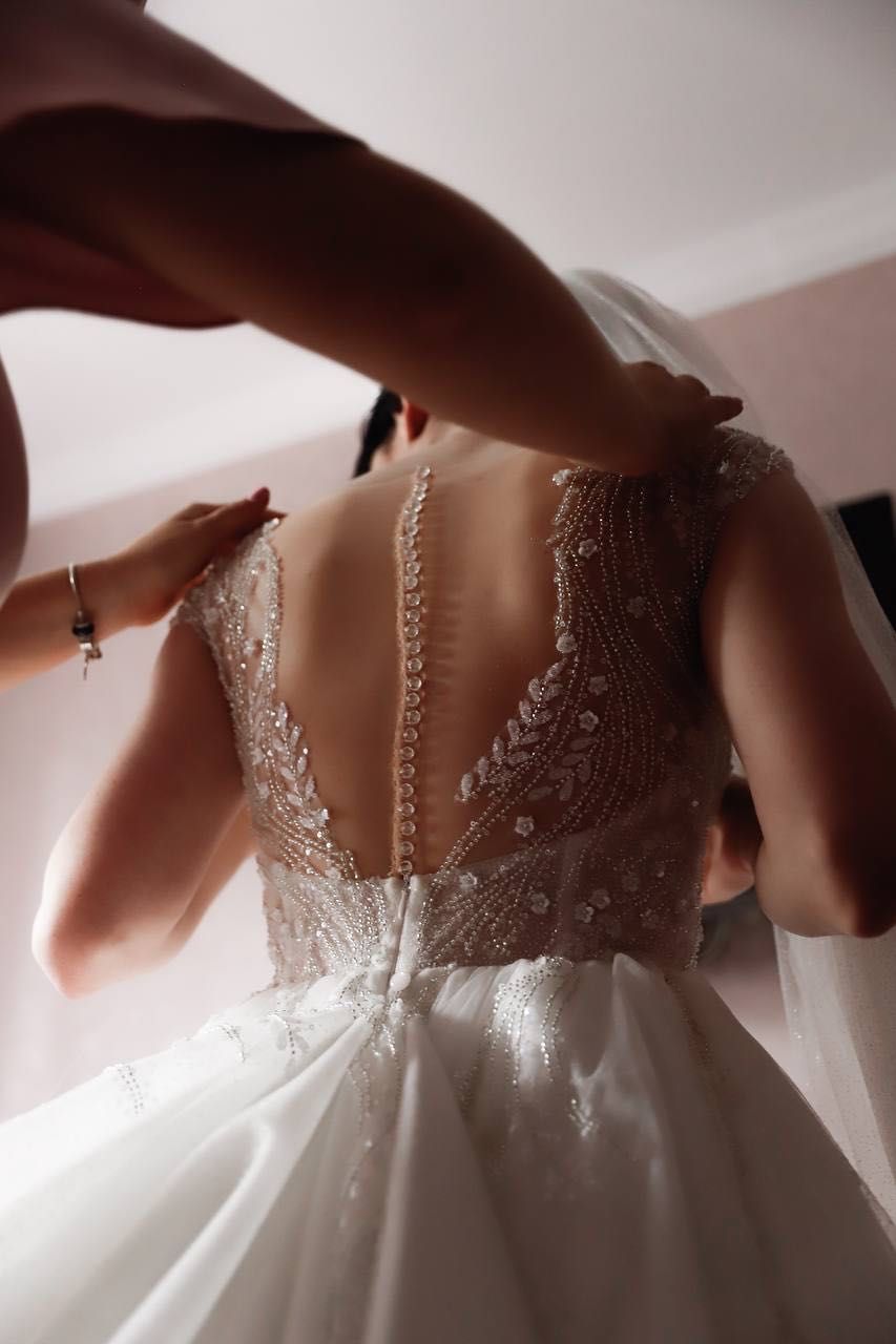 Весільна сукня зі шлейфом, пишне, обшите бісером з мереживом.