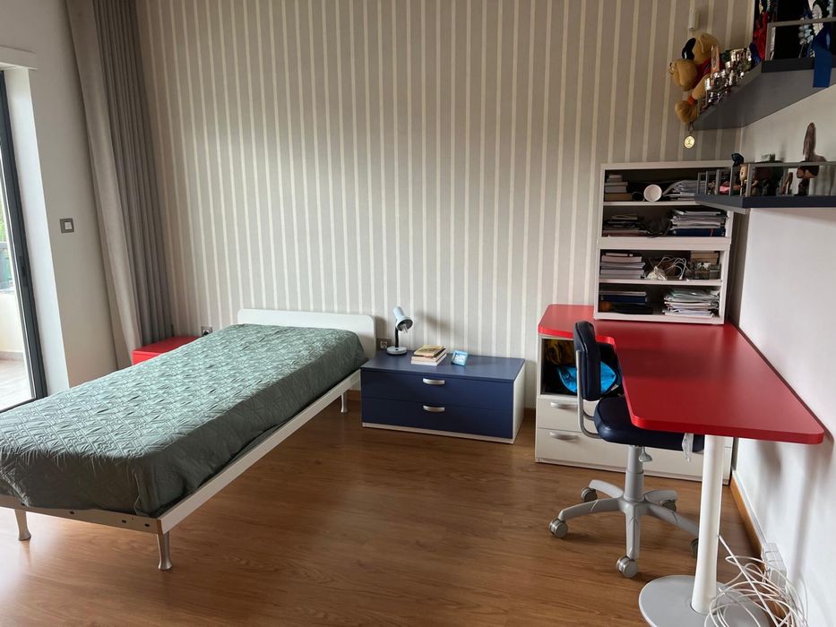 Quarto com cama , mesa de cabeceira e secretaria com estante