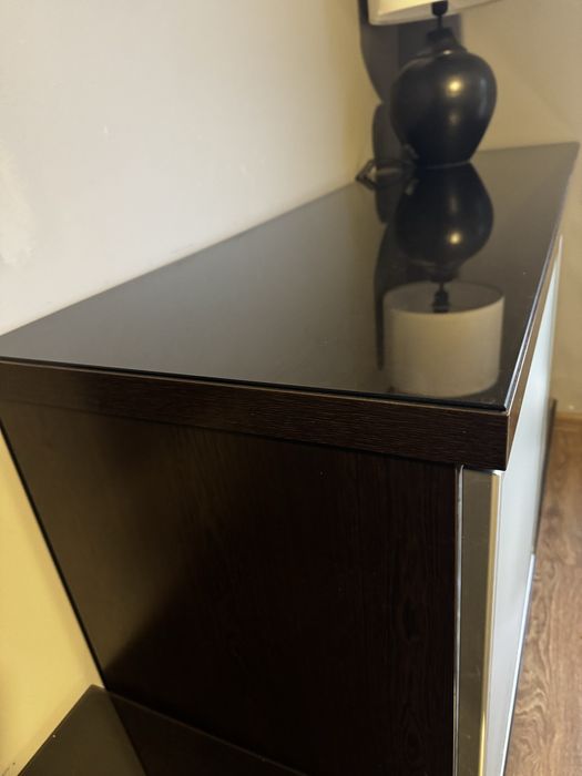 Czarna komoda z szufladami, szklany blat.