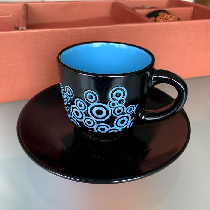 Caixa com quatro chávenas de café coloridas e pires.