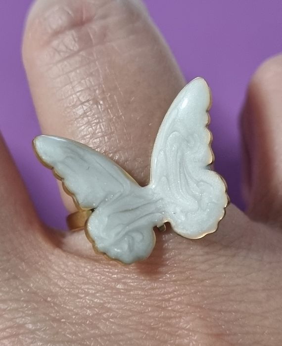 Anel dourado, em açol, com borboleta branca esmaltada. Ajustável