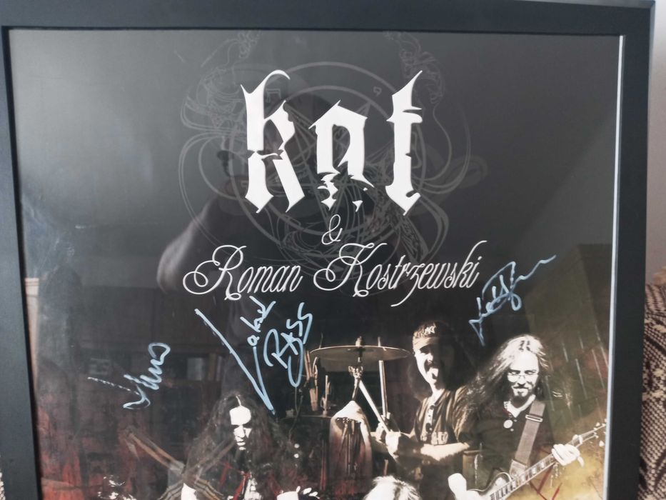 Plakat grupy KAT z autografami grupy w ramie.