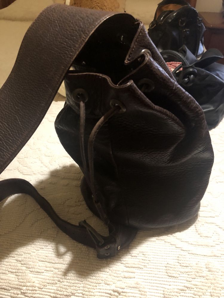 Mochila em pele castanha e bolsa preta . Ambas em pele