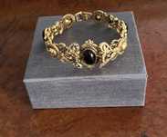 Pulseira dourada e pedras pretas