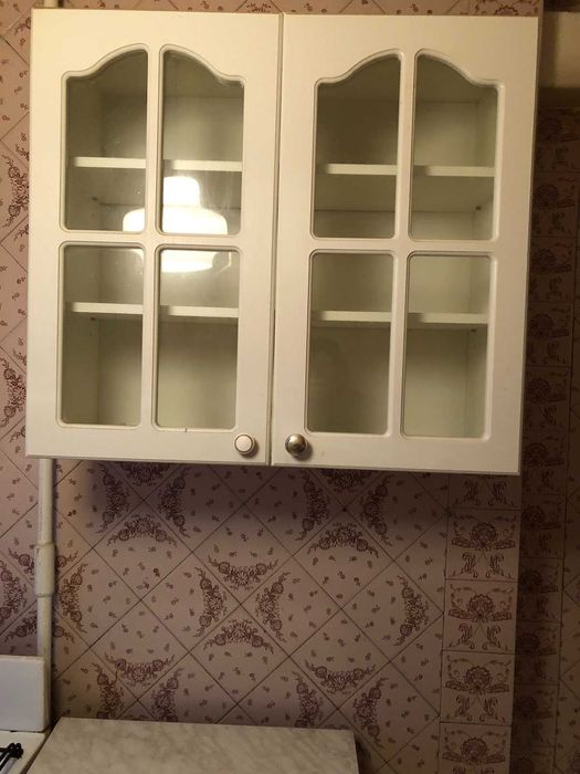 Белые тумбовые столы и навесные шкафчики.