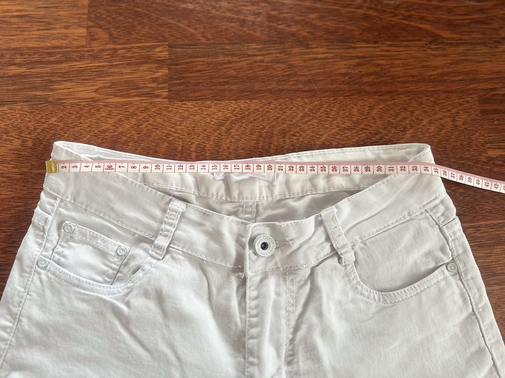 Białe spodnie z diurami na kolanach