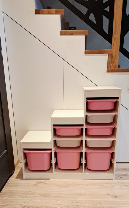 Regał IKEA TROFAST z pojemnikami – biały, różowe i beżowe skrzynki.