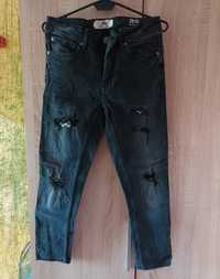 Czarne spodnie damskie z przetarciami podszytymi kraciastym materiałem