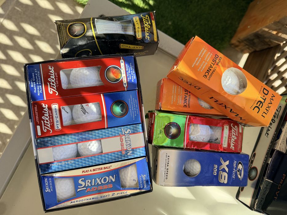 Bolas de golfe novas nas caixas e de treino