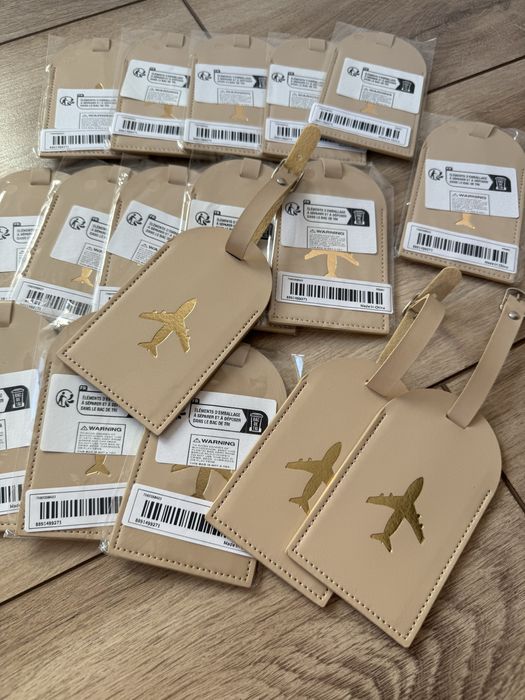 17 Beżowych zawieszek na bagaż ze złotym samolotem - prezent
