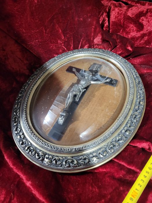 Stary krzyż w owalnej ramie za szkłem